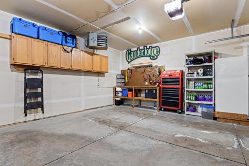 A second view of the heated garage shows cabinetry with ample space for a workbench and refrigerator.