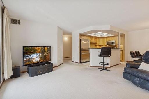 This condo unit features a bright, open living room that flows seamlessly into the kitchen and dining area.