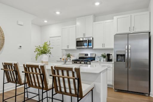(Photo is of a model home, finishes will vary) A multifunctional center island pairs with abundant cabinetry and all-new stainless steel appliances to create a sleek design in this breezy kitchen—perfect for cooking meals of all sizes.