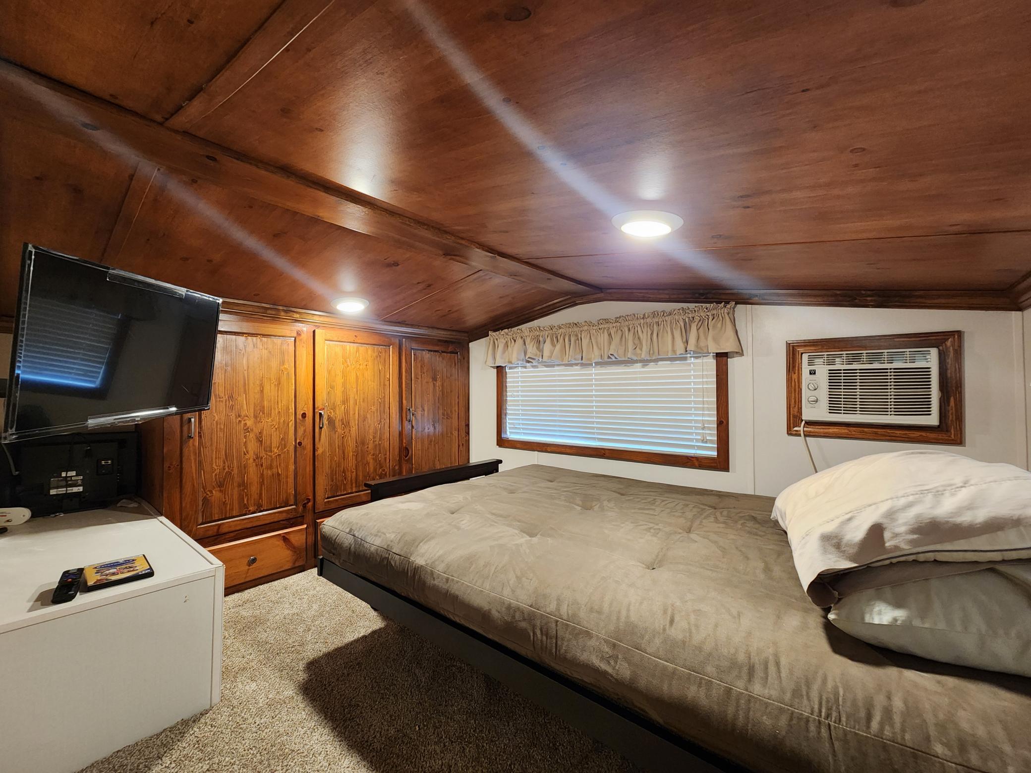 Private bedroom area of upper level of park model has built-ins and bed, etc.