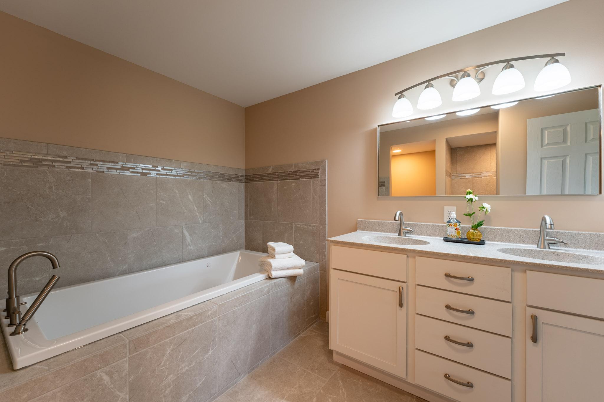 Newer Full Bathroom in the Lower Level, features a separate tub, walk-in shower, and double vanity.