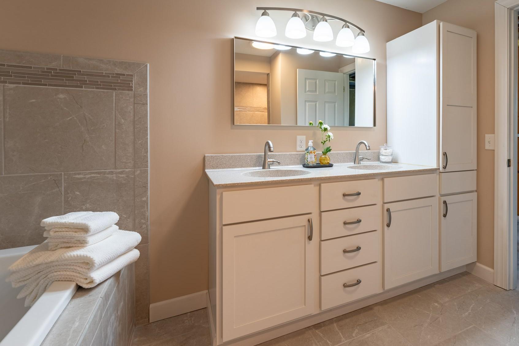 Newer Full Bathroom in the Lower Level, features a separate tub, walk-in shower, double vanity with tall storage cabinet and tile floor, shower and tub surround.