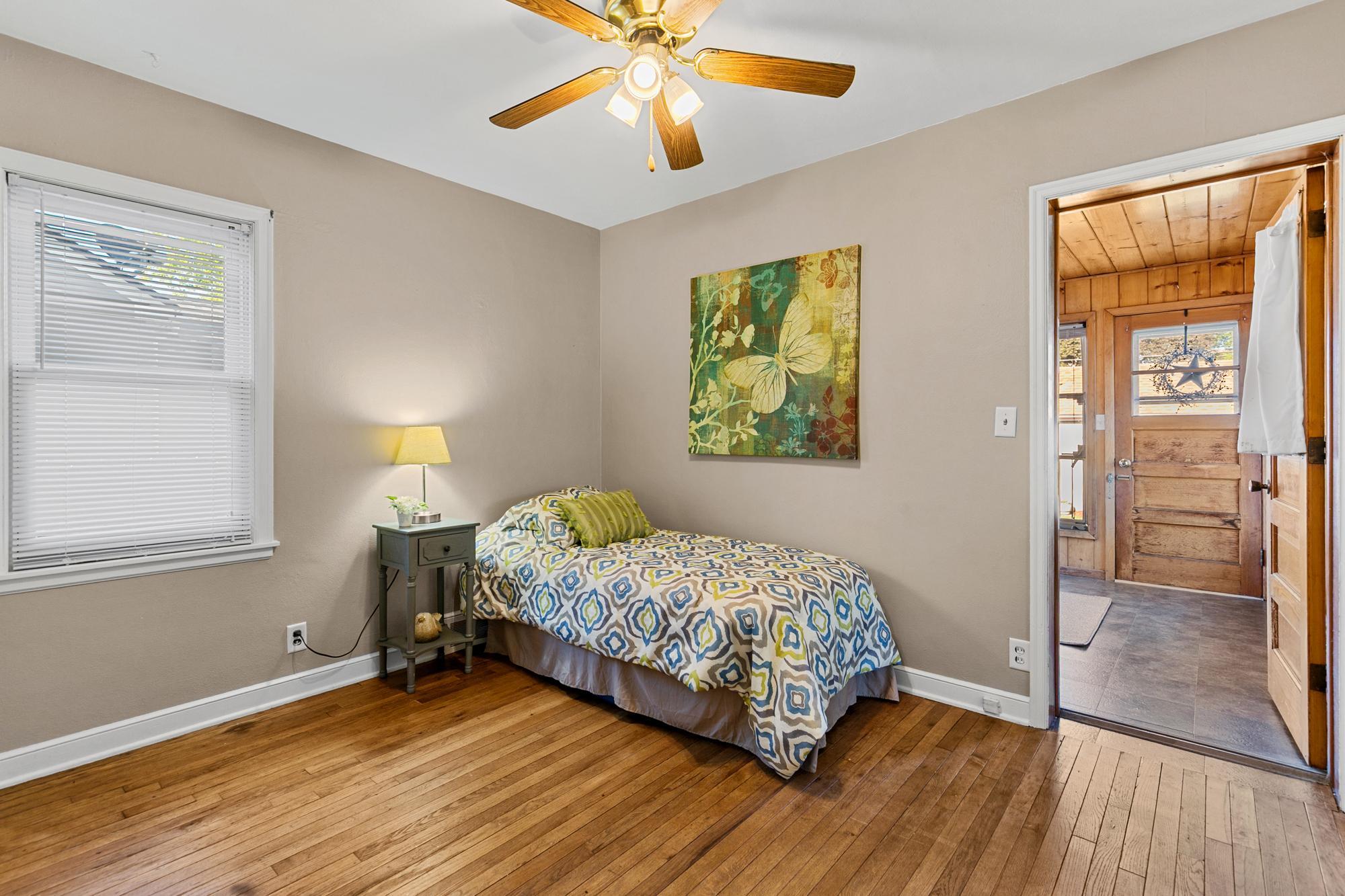 Main floor bedroom #2 with hardwood floors, fresh paint, ceiling fan and one of the entrances to the back porch.