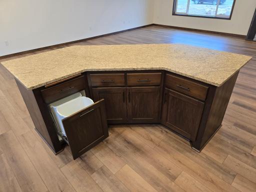 Large angled center island with snack bar overhang and built in recycling/garbage center.