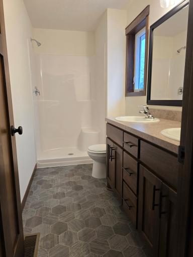 Primary Bathroom with double sinks, single casement window and 3x4 fiberglass shower.