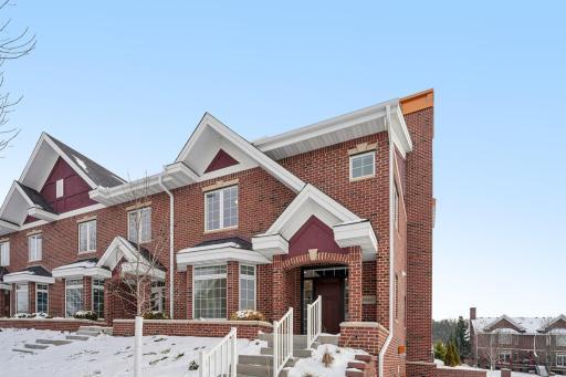Striking brick townhome exterior featuring timeless architecture, gabled rooflines, and an elevated setting that delivers strong curb appeal.