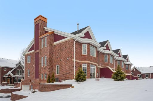 Brick townhome exterior highlighting end-unit positioning, architectural detailing, and the elevated setting within the community.
