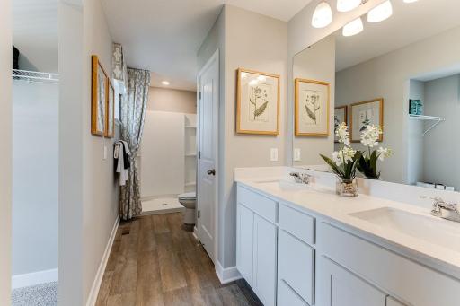 An extension of the primary suite, this private and spacious bathroom contains a double-vanity and large linen closet for an abundance of storage.