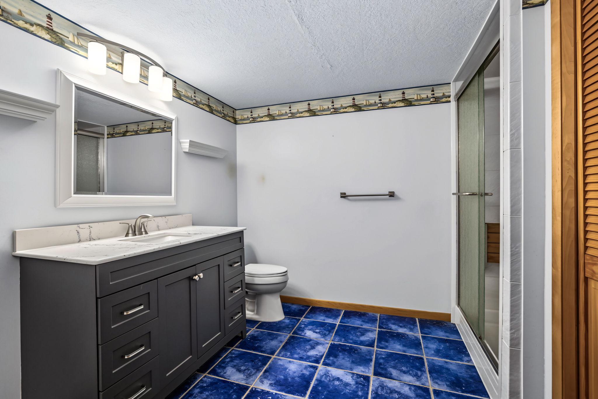 Lower level 3/4 bath with huge storage closet, updated vanity and tile flooring.
