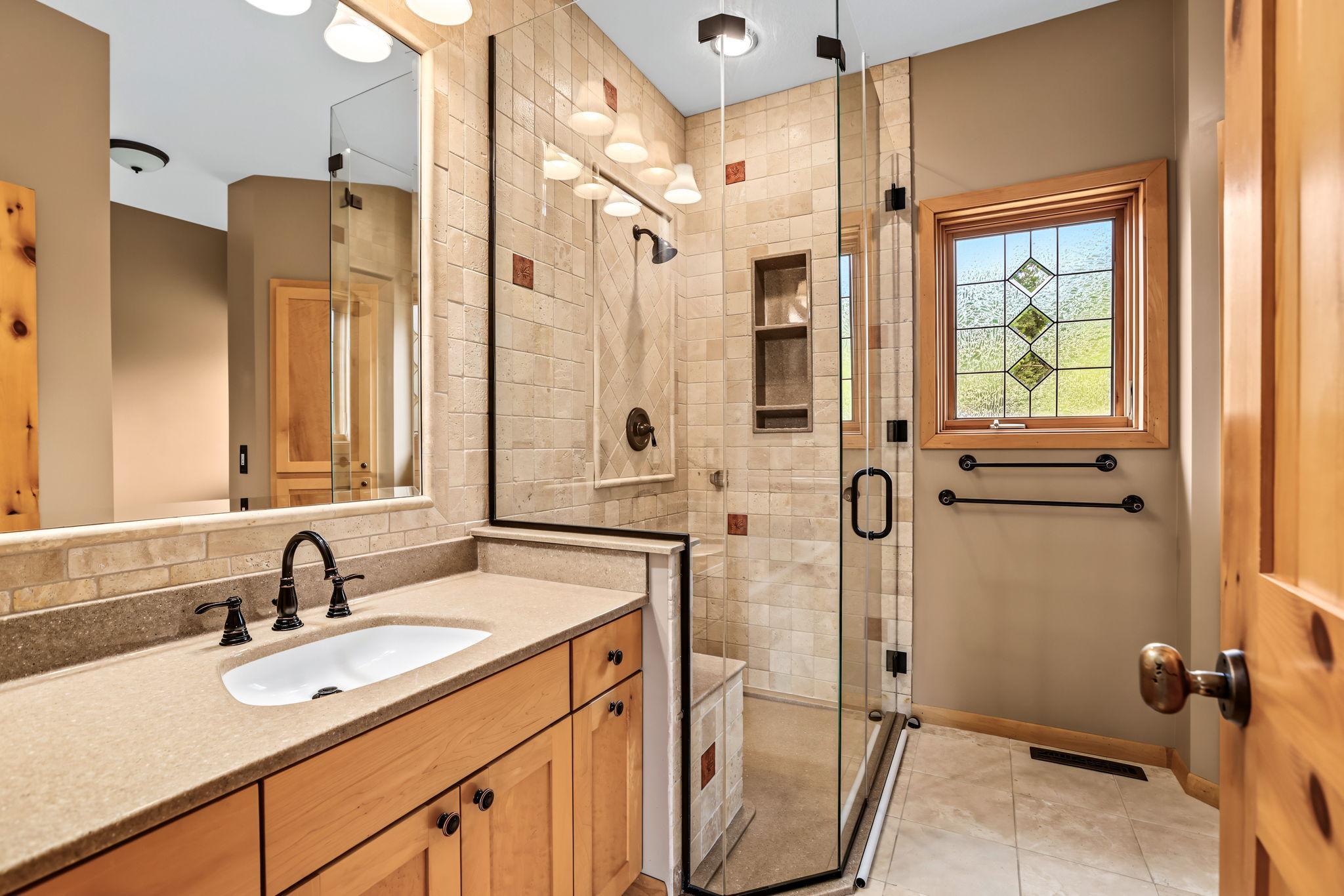 Fully renovated main floor primary bath with floor-to-ceiling custom tiled shower and jetted tub.