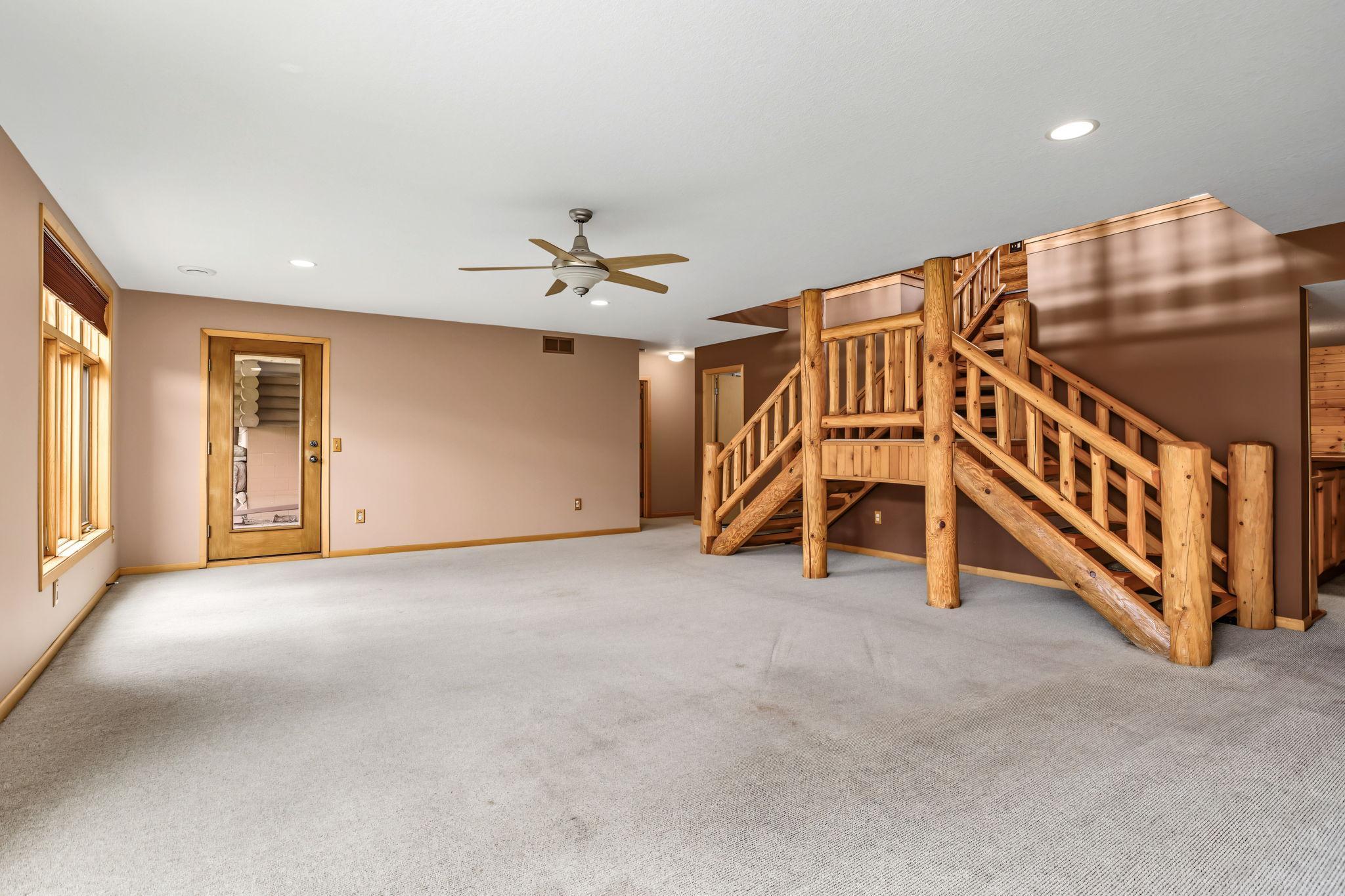 The expansive walkout lower-level family room offers a great space for entertaining. Recessed lighting, in-floor heat & oversized windows create a warm and inviting atmosphere, while the custom log staircase continues the home's Northwoods charm.