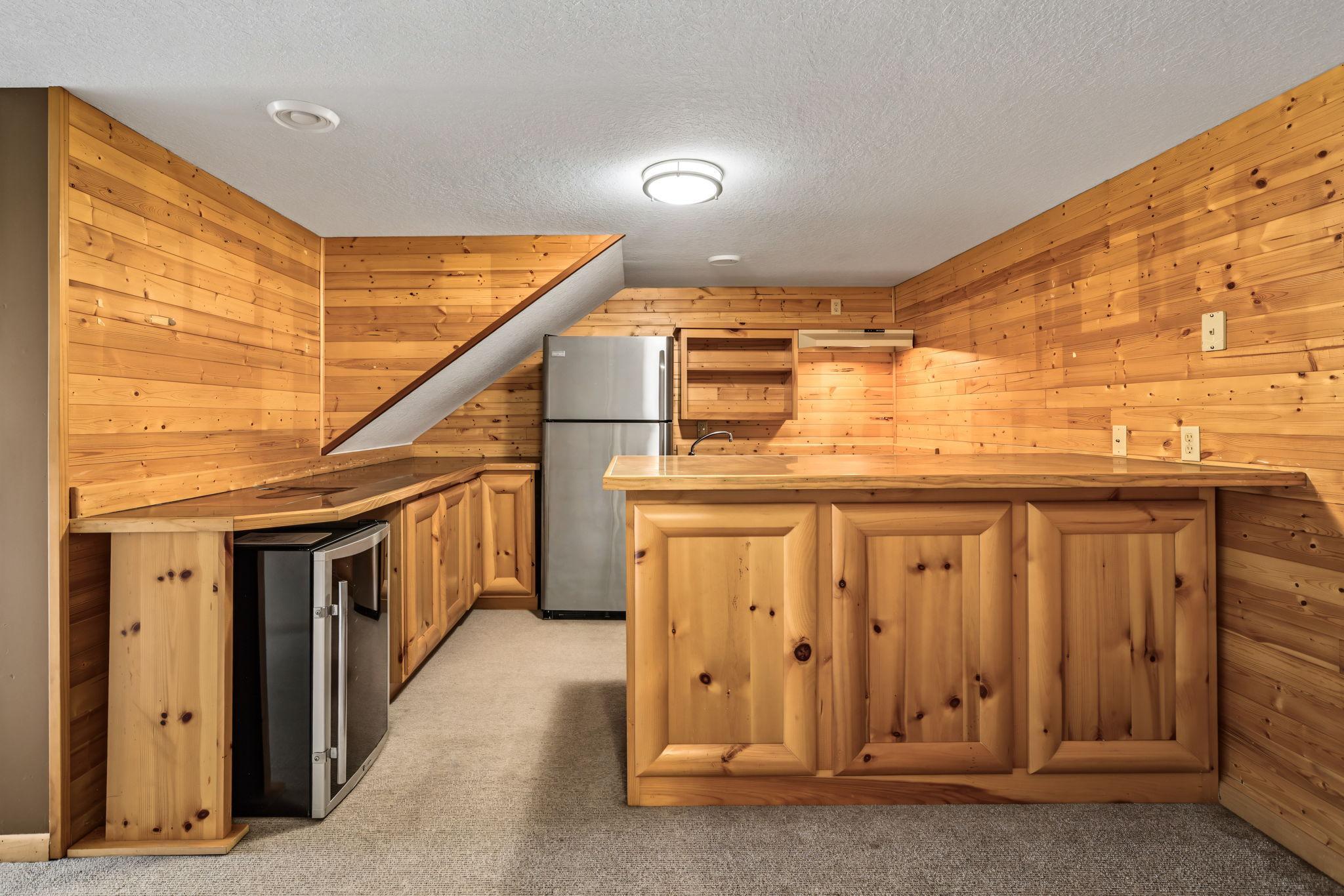 The walkout lower level is ideal for entertaining, featuring a rustic wet bar with knotty pine cabinetry, ample countertop space, beverage refrigerator, sink and room to gather with family and friends.