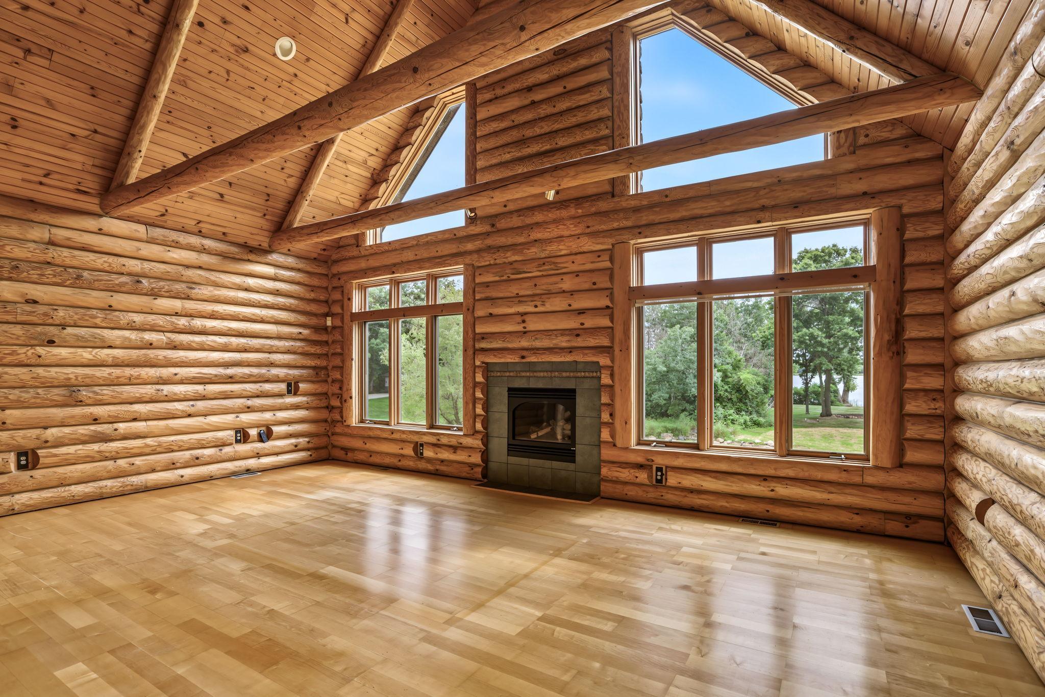 Breathtaking two-story great room features soaring tongue-and-groove ceilings, massive exposed beams, a cozy gas fireplace and a dramatic wall of windows framing beautiful views of Otter Lake.