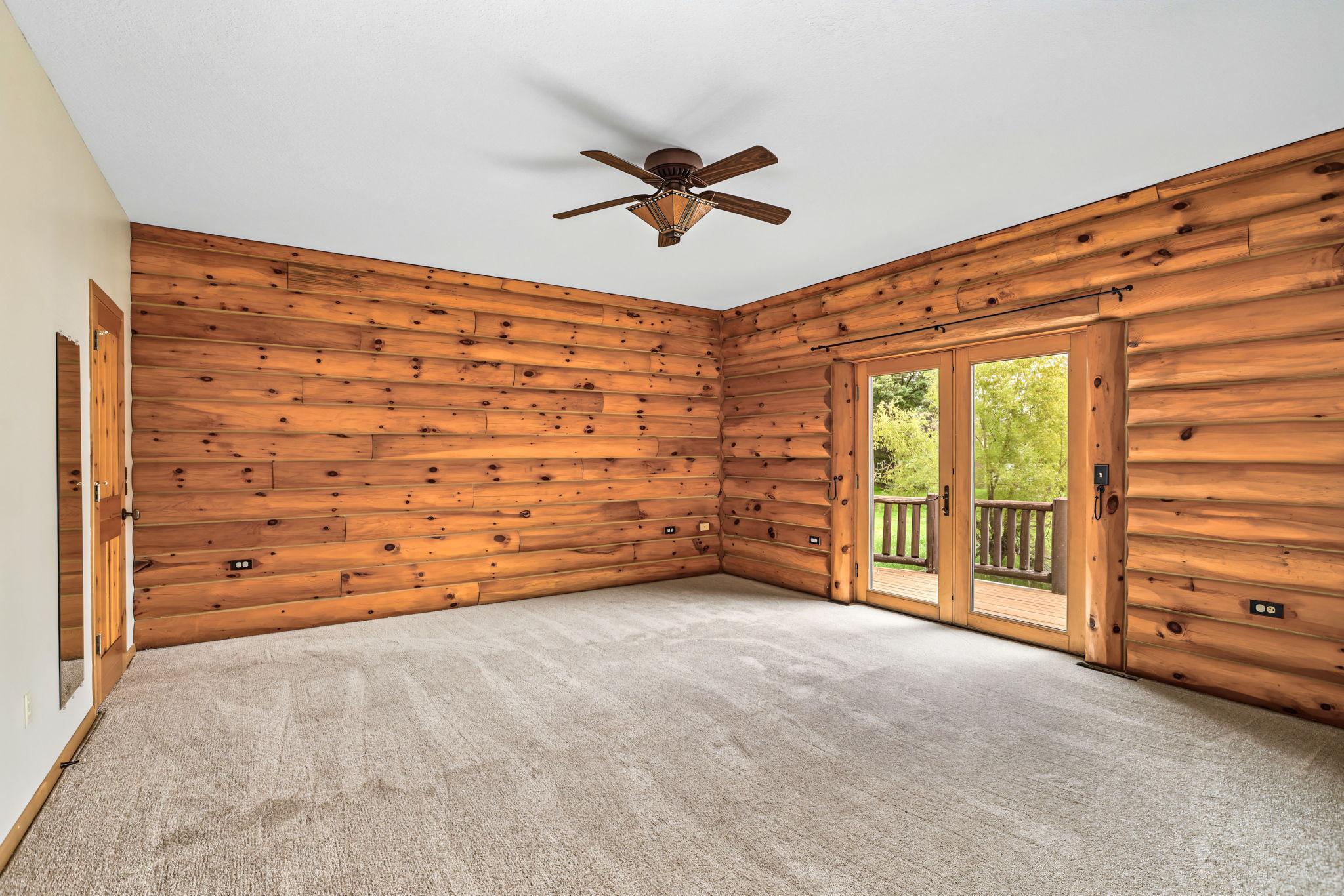 Wake up to peaceful backyard views from the spacious main-floor primary suite featuring private deck access, walk-in closet, and a renovated bath with tile flooring, jetted tub, and separate shower.