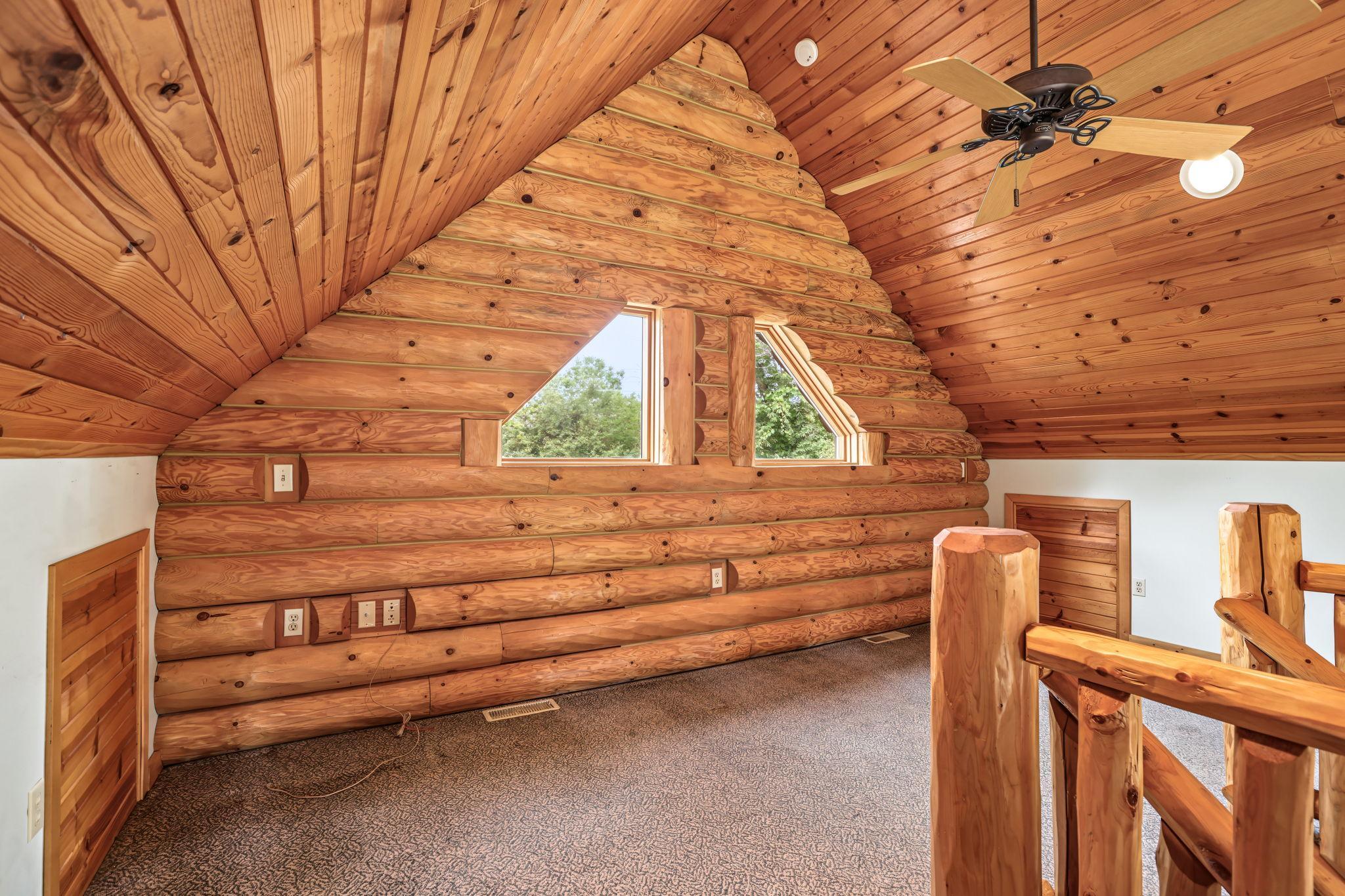 Overlooking the dramatic 2-story great room, the upper-level loft offers a versatile space for a home office or creative studio. Vaulted tongue-and-groove wood ceilings, log accents and unique architectural windows enhance the home's warm character.