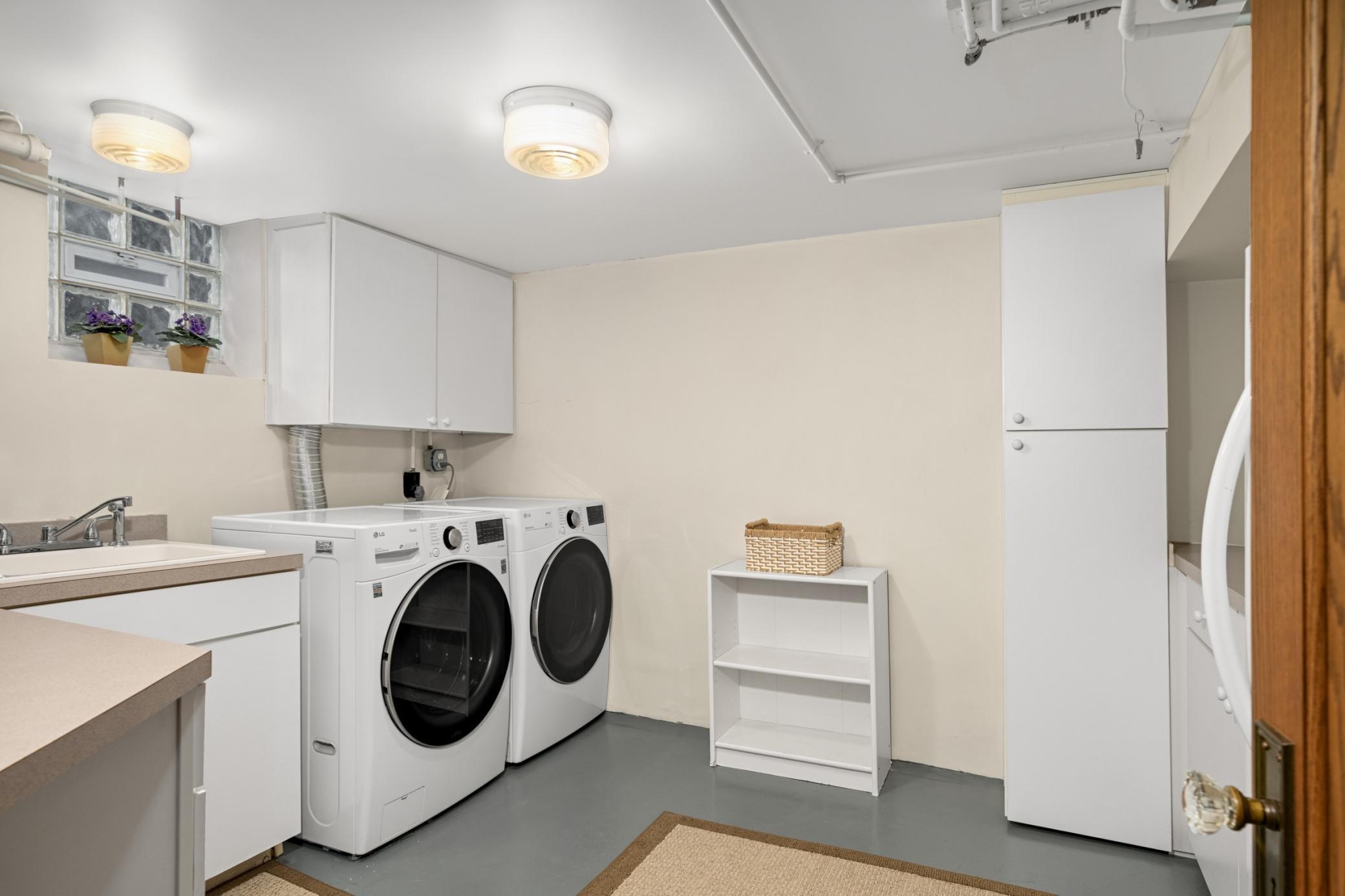 Lower level Laundry room with sink, cabinetry, and freezer.