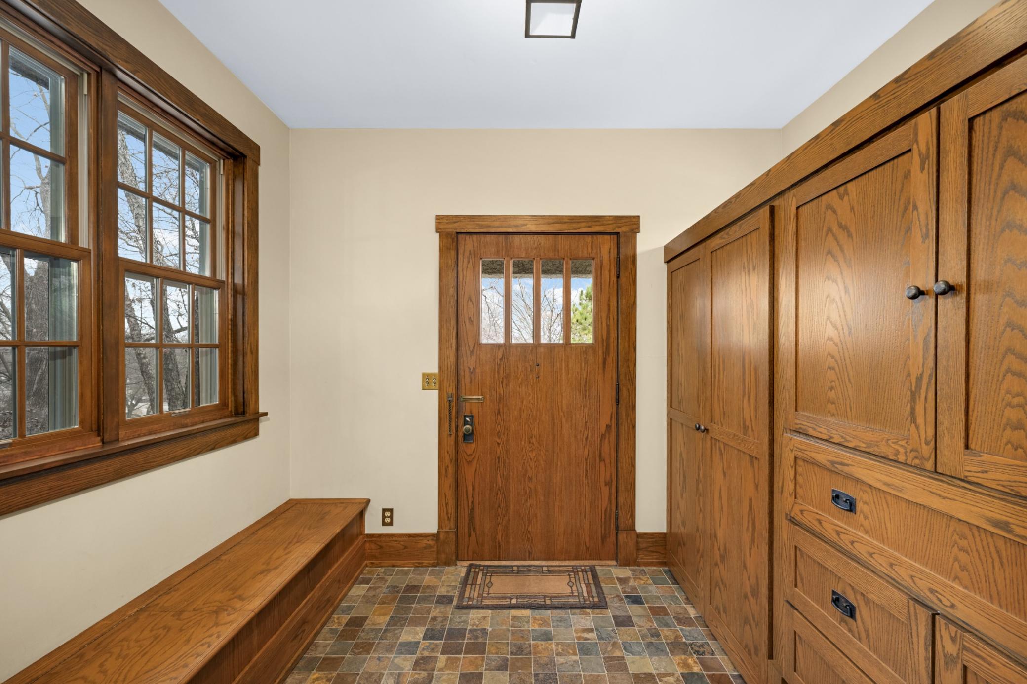 Front foyer with built-ins, bench, and tile.