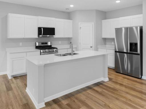 Photo of a different home with similar finishes and plan. Kitchen features a center island and corner walk-in pantry.