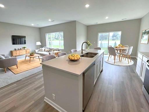 Virtually staged photo of a different home with similar finishes and plan. Kitchen open to dining room and great room.