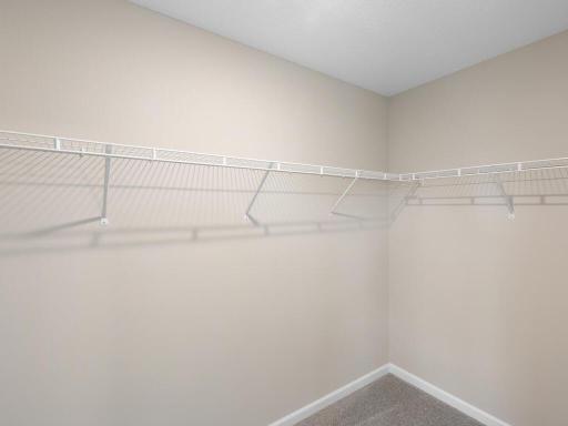 Primary Suite Walk In Closet. Photo taken of another home with similar plan and finishes. Photos and renderings may not depict actual plan, materials, & finishes may vary. All measurements are approximate.