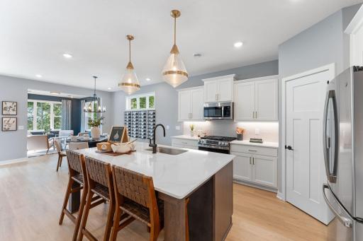 The heart of the home! Kitchen features a spacious center island with sink, tiled backsplash and undercabinet lighting.