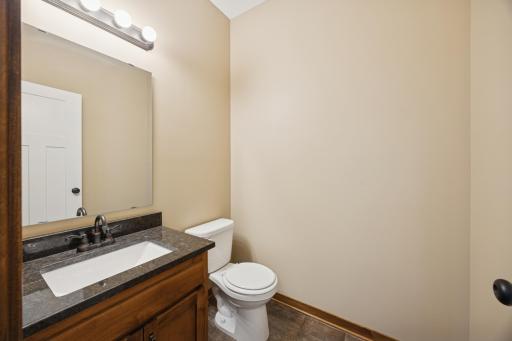 Main level half bathroom offering granite countertop, quality cabinetry, and easy-to-maintain flooring.
