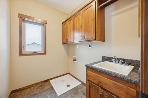 Functional main level laundry room with utility sink, built-in cabinetry, and washer/dryer hookups.
