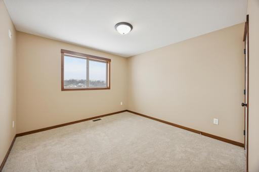 Fourth well-sized bedroom with a spacious walk in closet with new carpet and large window overlooking the property.