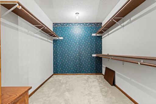 Spacious walk-in primary closet featuring extensive hanging space, built-in shelving, and abundant storage for organization and everyday convenience