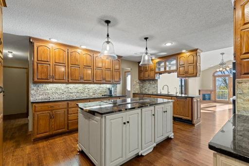 Spacious kitchen featuring custom cabinetry, expansive prep space, hardwood floors, and an open layout connecting seamlessly to surrounding living areas