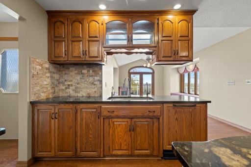 Custom built-in serving station with sink, extensive cabinetry, stone backsplash accents, and added prep space designed for effortless entertaining.