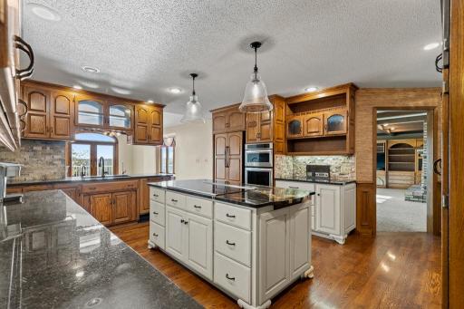 Spacious kitchen featuring rich custom cabinetry, center island, hardwood floors, abundant prep space, and an open layout designed for everyday living and entertaining.