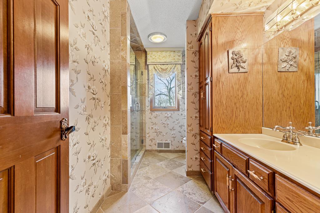 Updated bathroom featuring extensive custom cabinetry, spacious vanity, and elegant finishes throughout.
