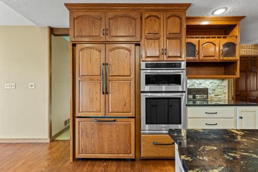 Thoughtfully designed kitchen showcasing floor-to-ceiling custom cabinetry, convection wall oven, and exceptional storage space.