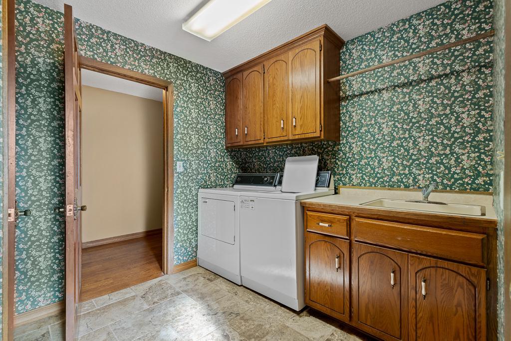 Spacious main-level laundry room featuring utility sink, abundant cabinetry, and extra workspace for everyday convenience and organization