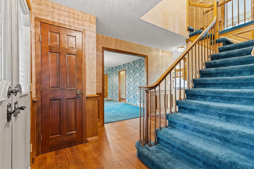 Welcoming foyer featuring hardwood floors, classic staircase details, and an inviting layout connecting the home's living spaces.