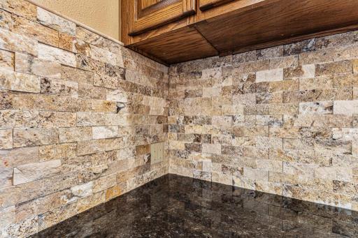 Beautiful natural stone backsplash adding warmth, texture, and custom design details throughout the kitchen space.