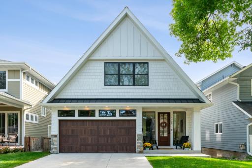 Covered front porch with modern wood door and oversized windows.