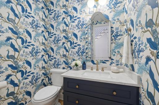 Stylish main-level powder bath with statement wallpaper, custom vanity, and designer lighting.
