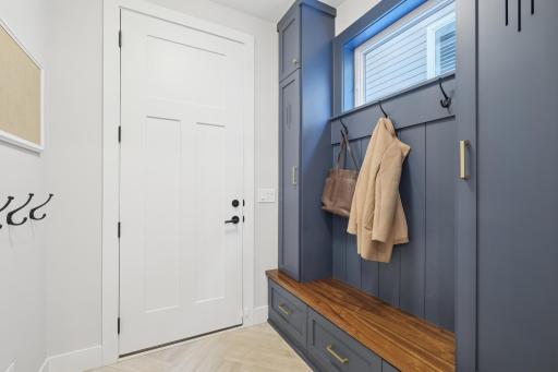 Functional mudroom from the garage with built-in storage, bench seating, and tile flooring.