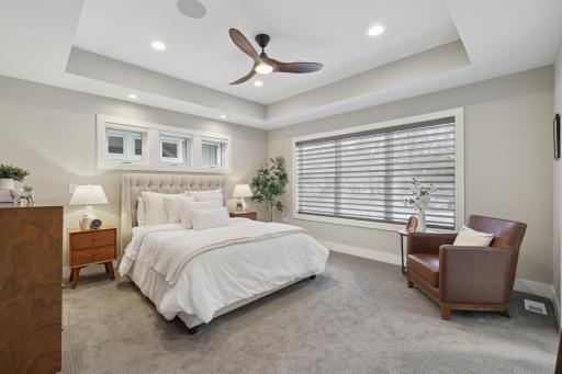 Spacious primary bedroom with tray ceiling, recessed lighting, and ceiling fan.