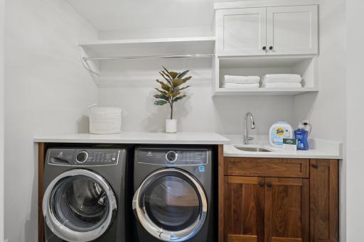 Convenient upper-level laundry with sink and cabinetry.