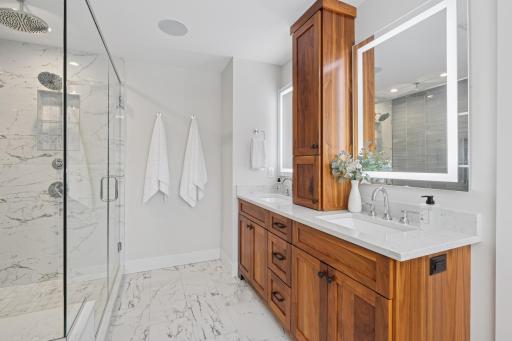 Dual vanity with custom cabinetry, quartz countertops, backlit mirrors and heated floors.