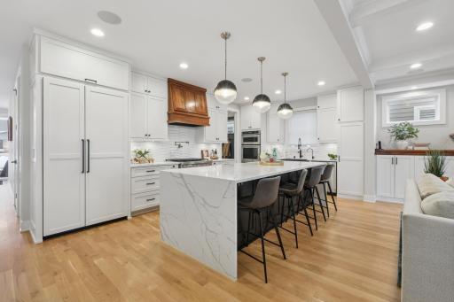 Chef's kitchen with quartz waterfall island, custom cabinetry, and premium appliances.