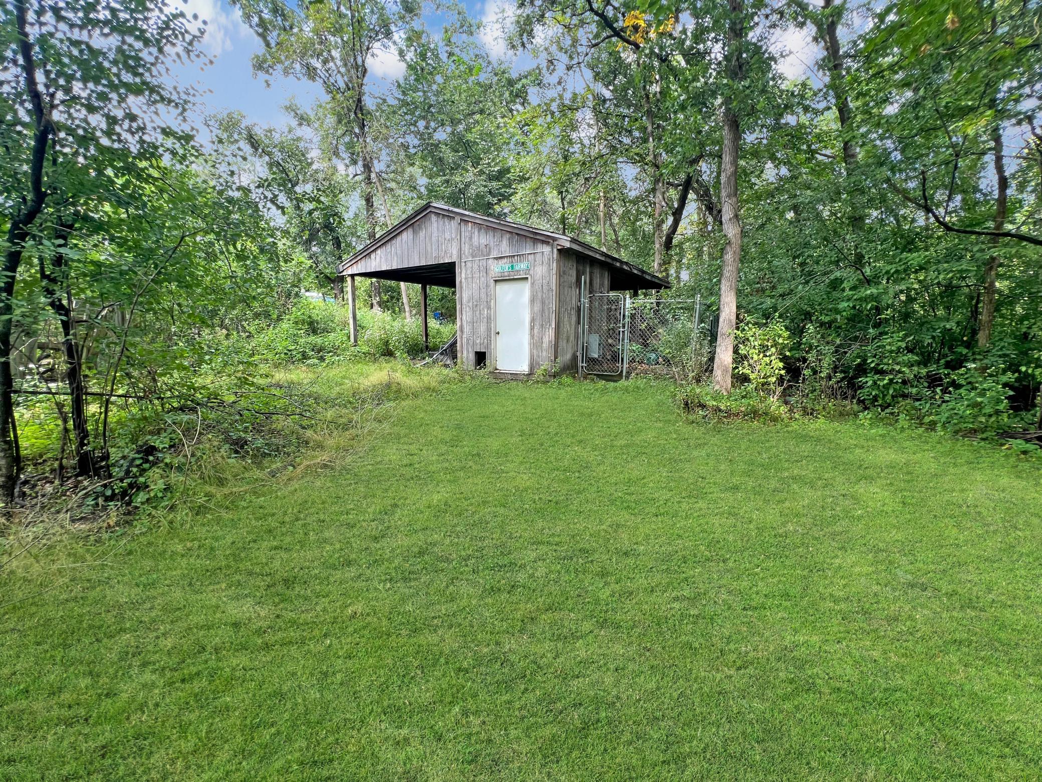 Outbuilding / Storage shed includes space for a vehicle to park and dog kennel.