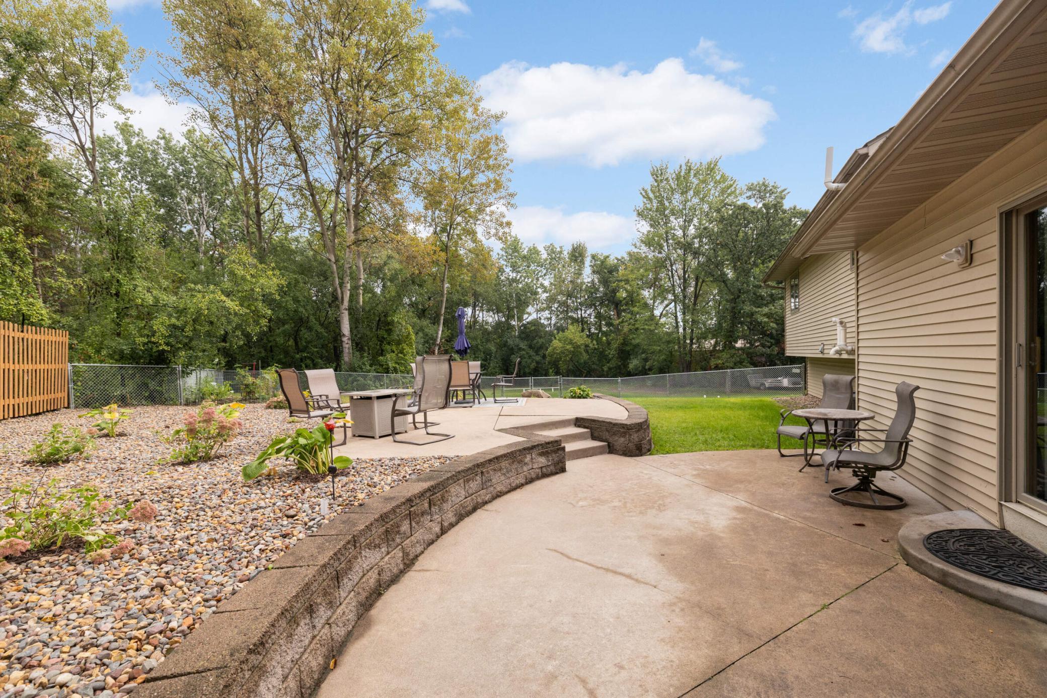 Multiple patio areas with a fenced section for pets or kids plus additional yard beyond.