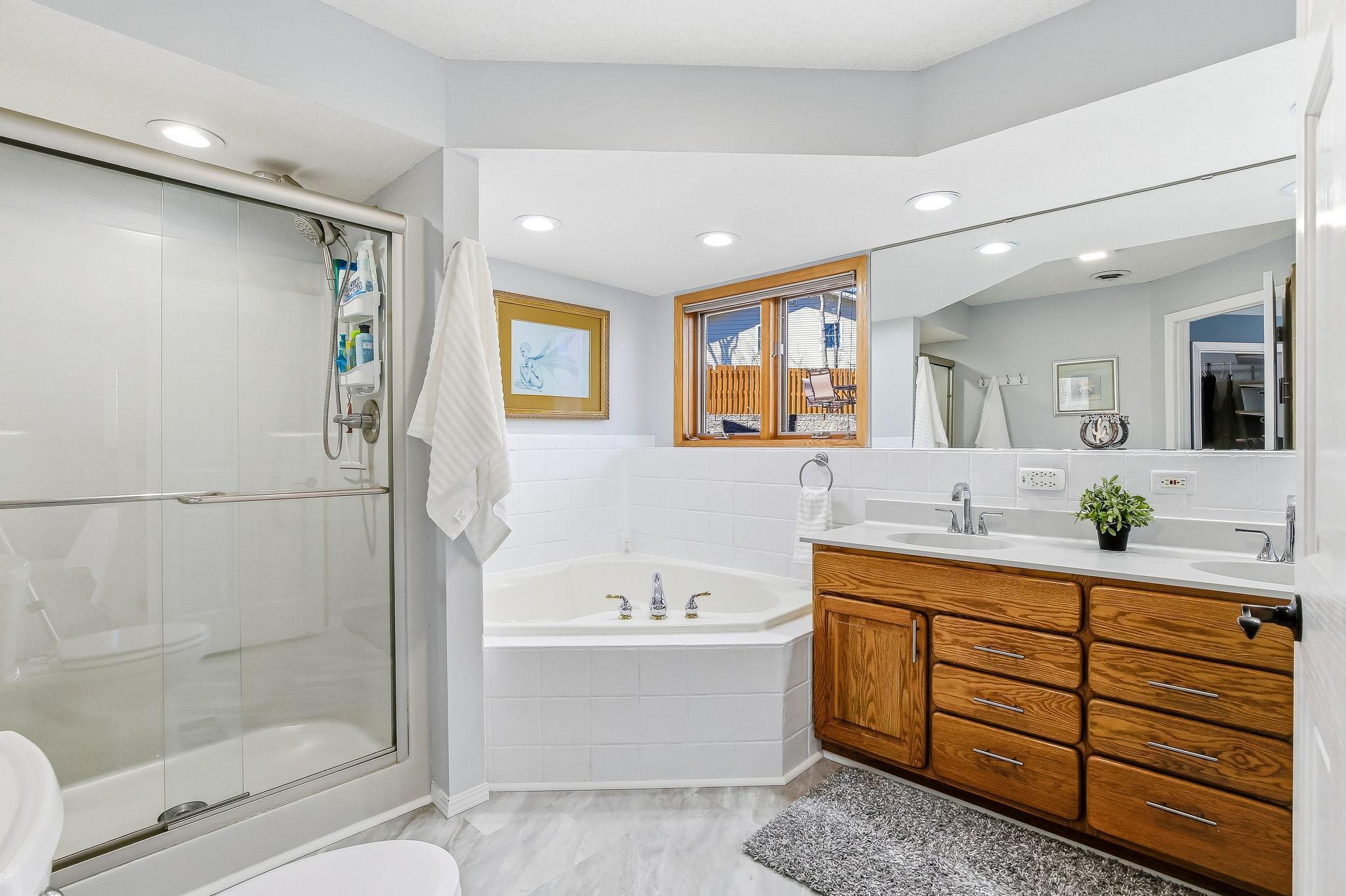 Private Bath with double sinks, Jacuzzi tub, walk-in shower, and updated flooring.