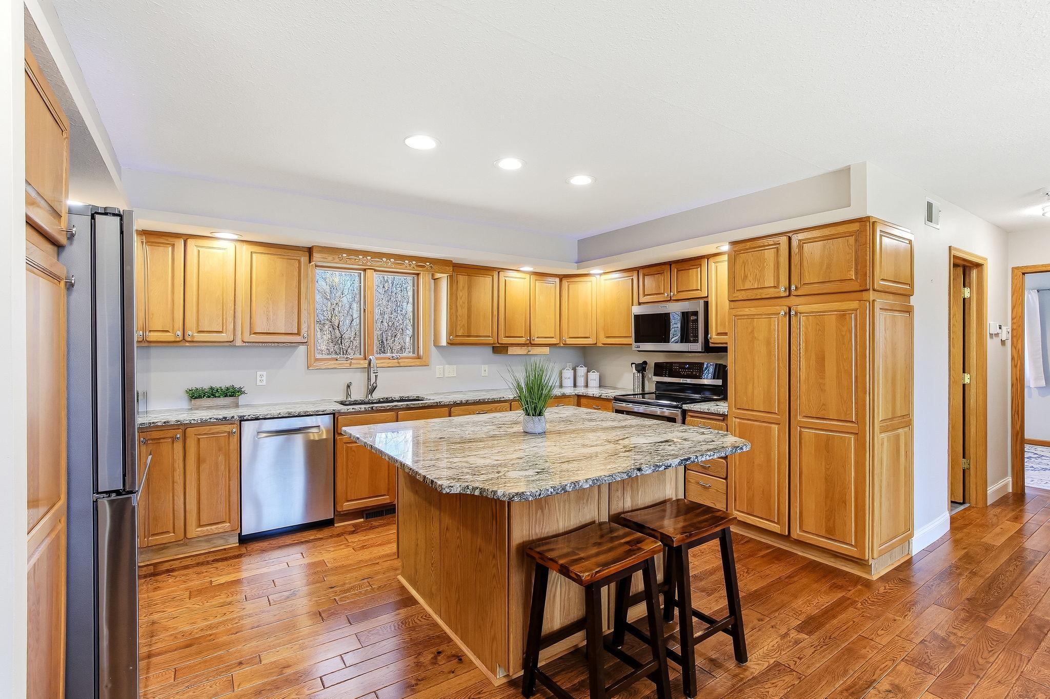 Spacious Kitchen with granite countertops, large center island, stainless steel appliances, and hardwood floors.