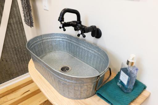 Sink crafted from an old tin wash tub, adding rustic character and one-of-a-kind charm to the half bath