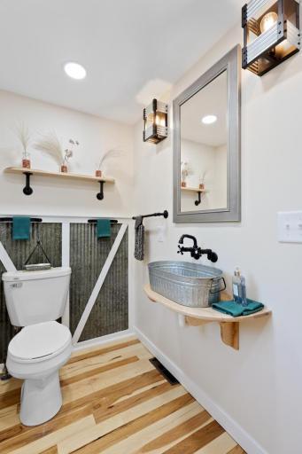 Main-level half bath with custom finishes and tin accents, blending a touch of rustic outdoor charm with a modern design.